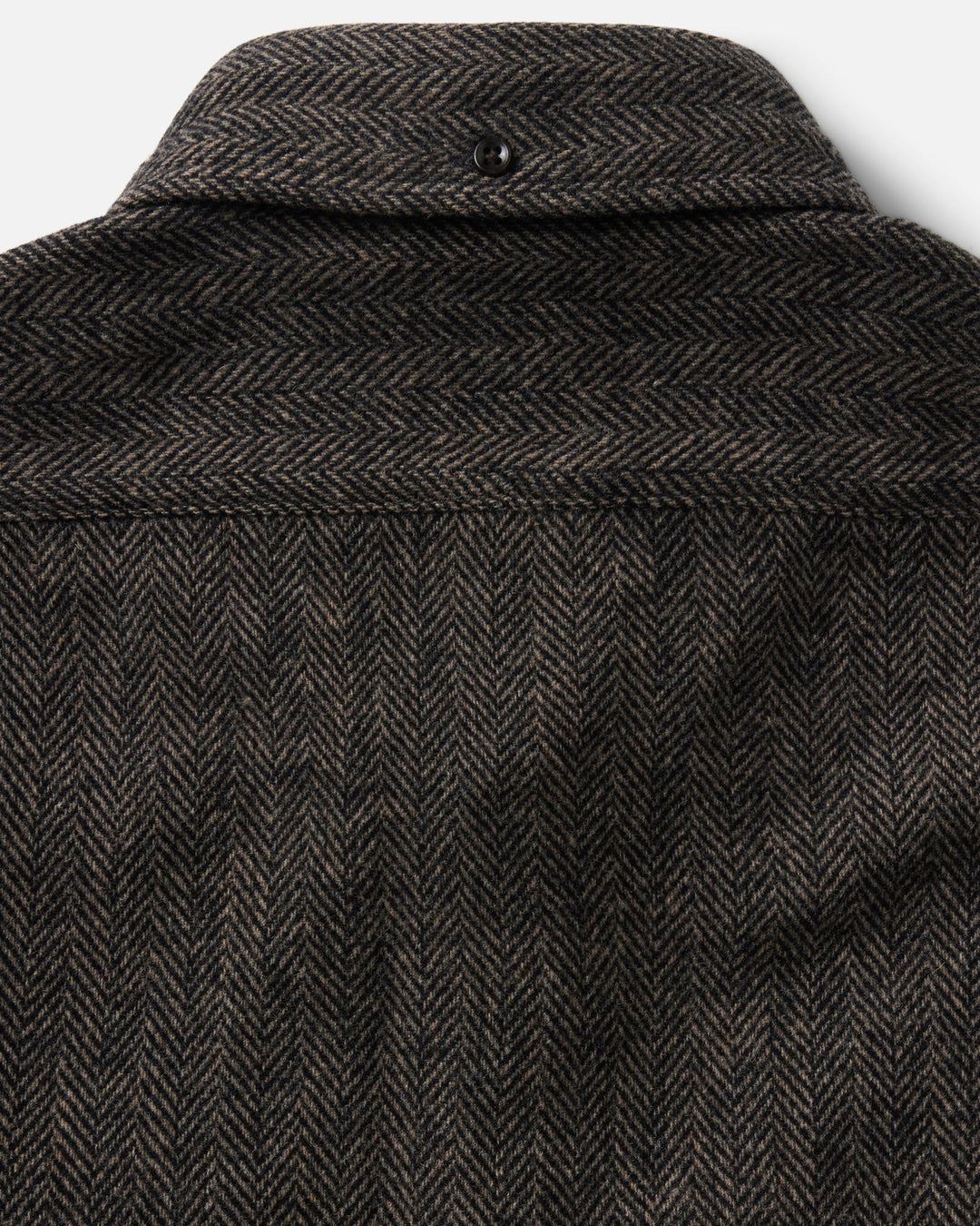 Close-up of the back of a dark brown and black herringbone tweed jacket, showing the collar, button, and detailed fabric weave.