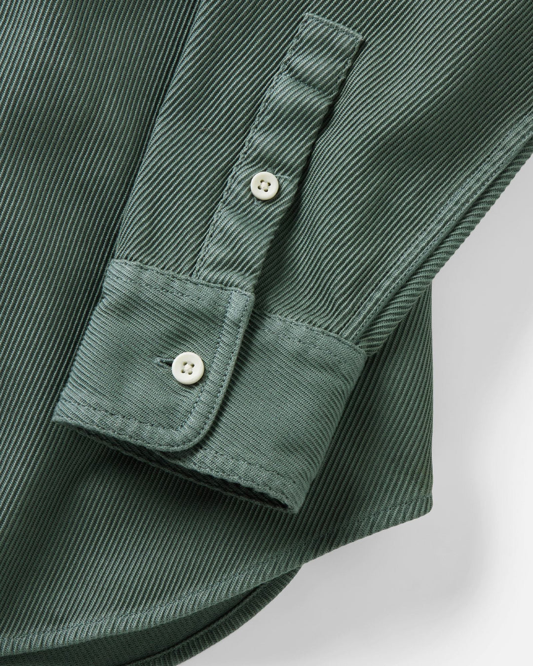 Close-up of a ledge deep sea shirt sleeve with two white buttons on a light gray background.