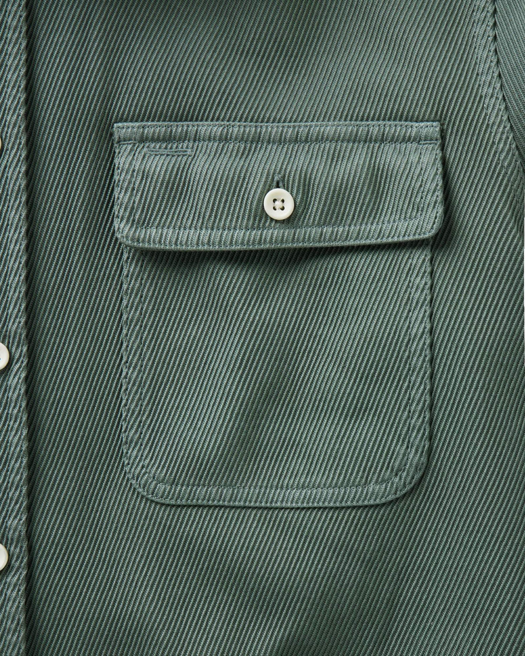 Close-up of a ledge deep sea shirt jacket showing a chest pocket with a button flap and a silver snap button.