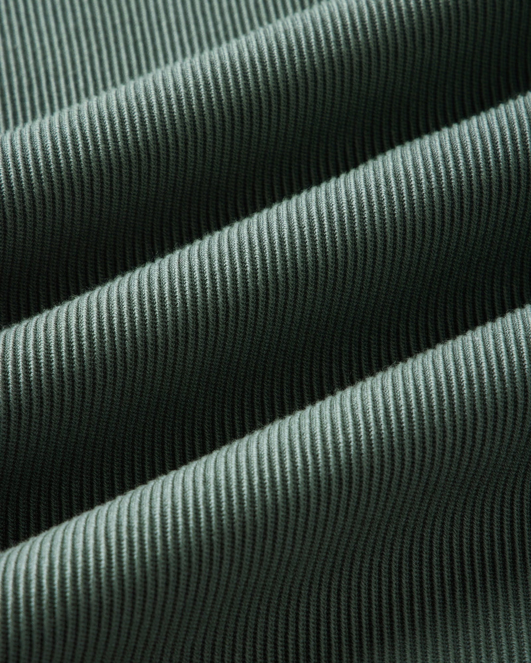 A close-up of deep sea ribbed fabric with a fine vertical corduroy-like texture, shown in soft folds.