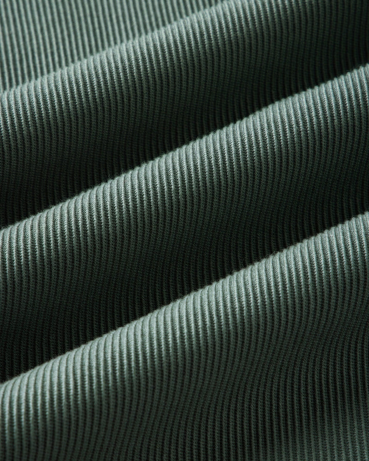 A close-up of deep sea ribbed fabric with a fine vertical corduroy-like texture, shown in soft folds.