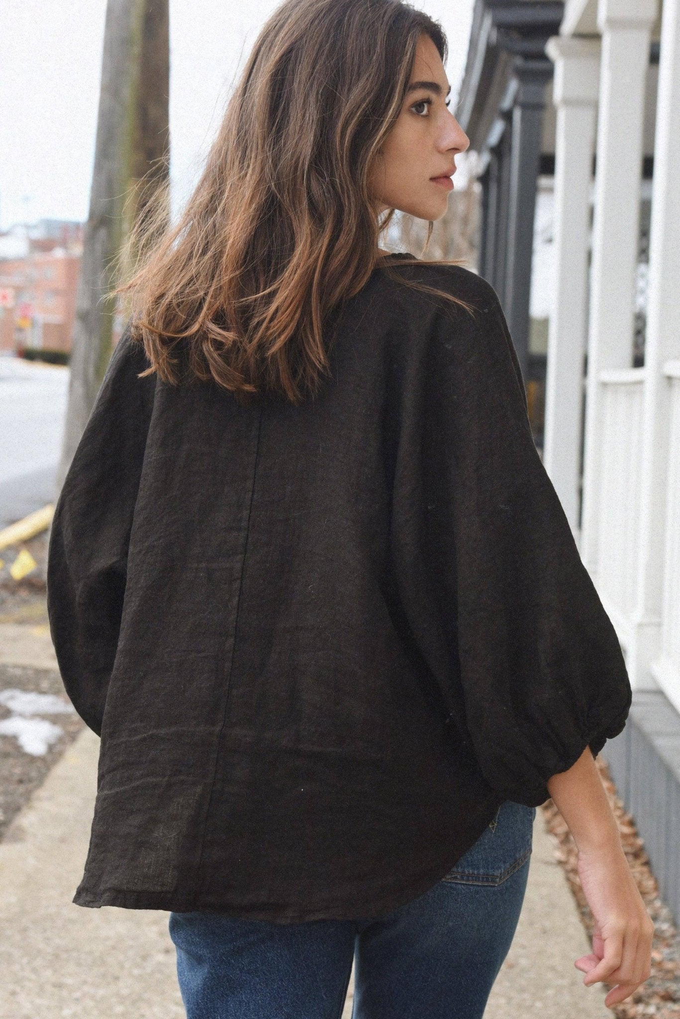 Woman wearing a black oversized shirt and blue jeans outdoors.