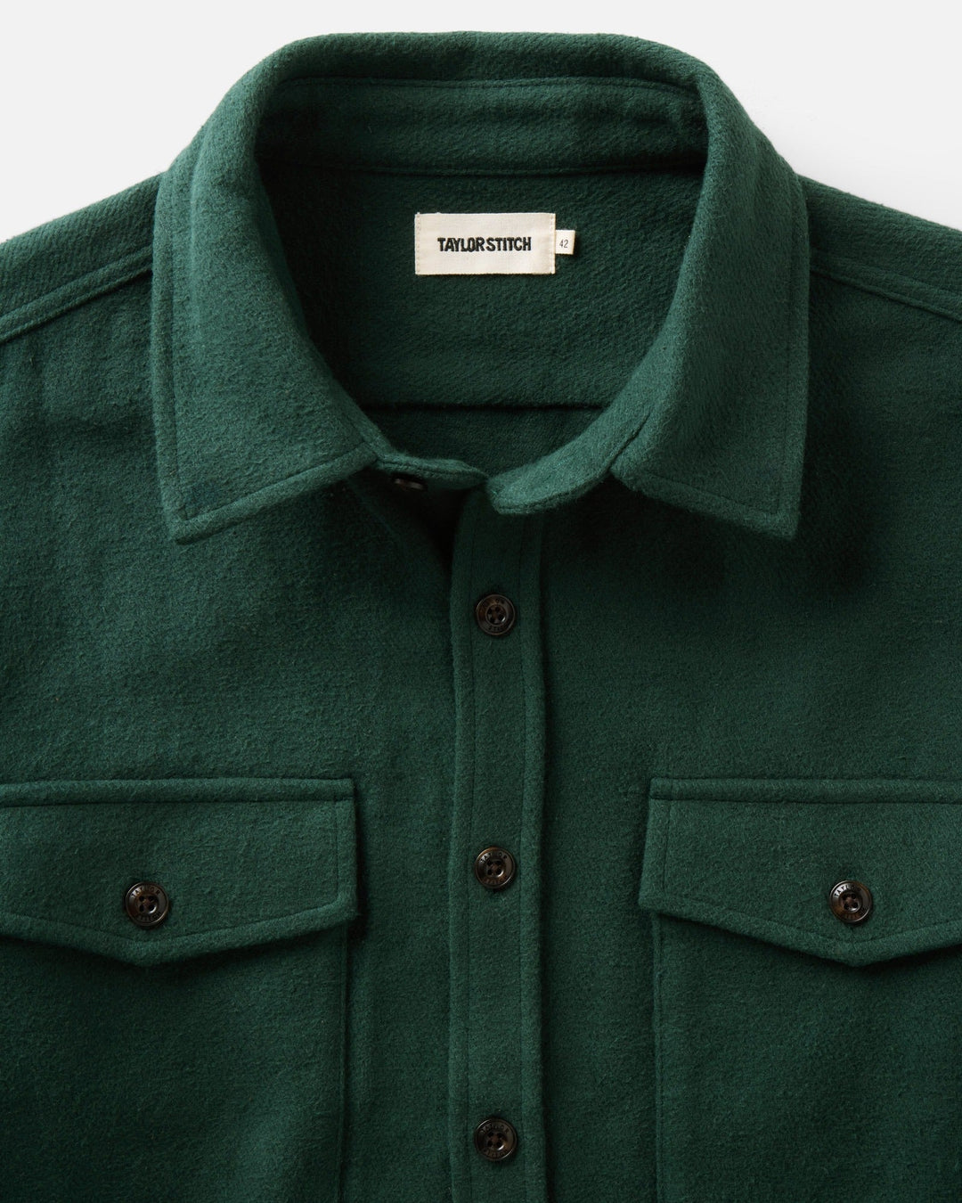 Close-up of a dark forest maritime button-up shirt jacket by Taylor Stitch, featuring a classic collar, button-down front, and two chest flap pockets.
