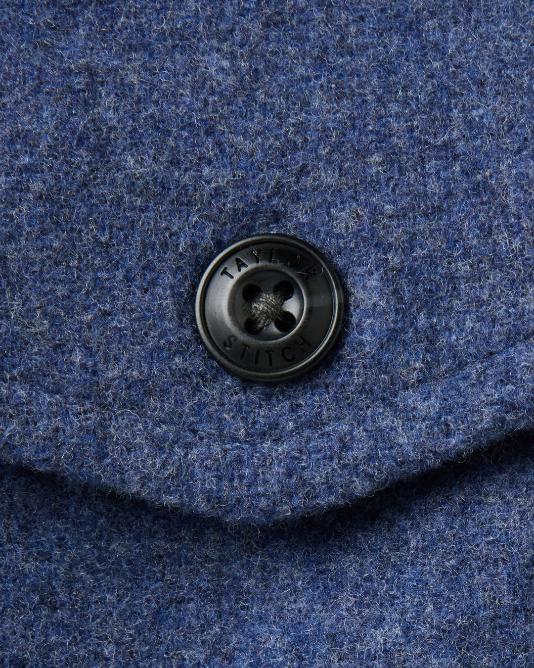 Close-up of The Maritime Shirt Jacket
in Heather Navy Wool with a dark metal button featuring the brand name &
