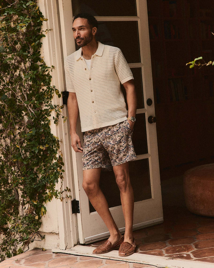 Man standing in front of a door wearing The Monterey Sweater Polo in Vintage White Crochet and shorts.