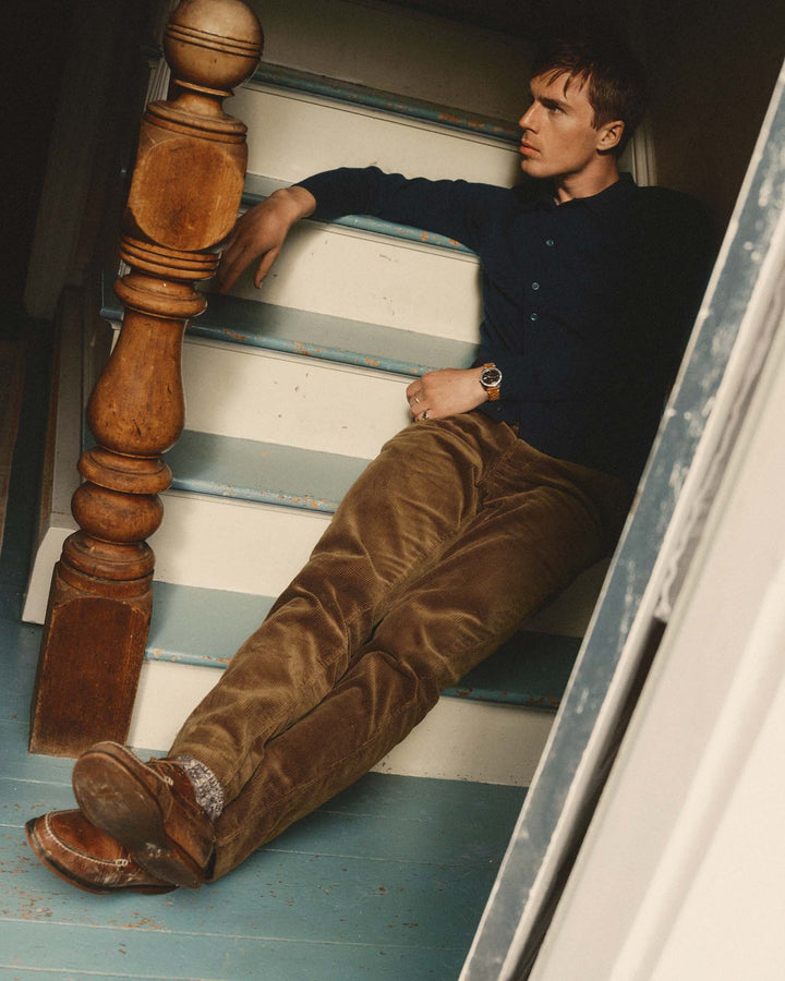 A man reclining on painted wooden stairs, wearing Taylor Stitch&