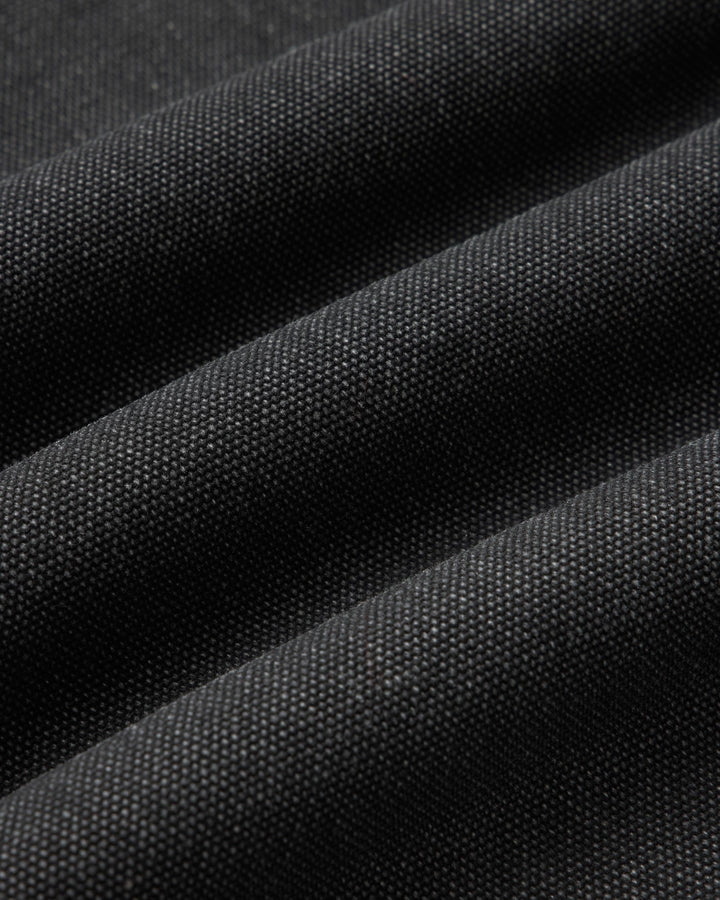 A close-up of dark charcoal gray fabric with a fine woven texture, shown in soft diagonal folds.