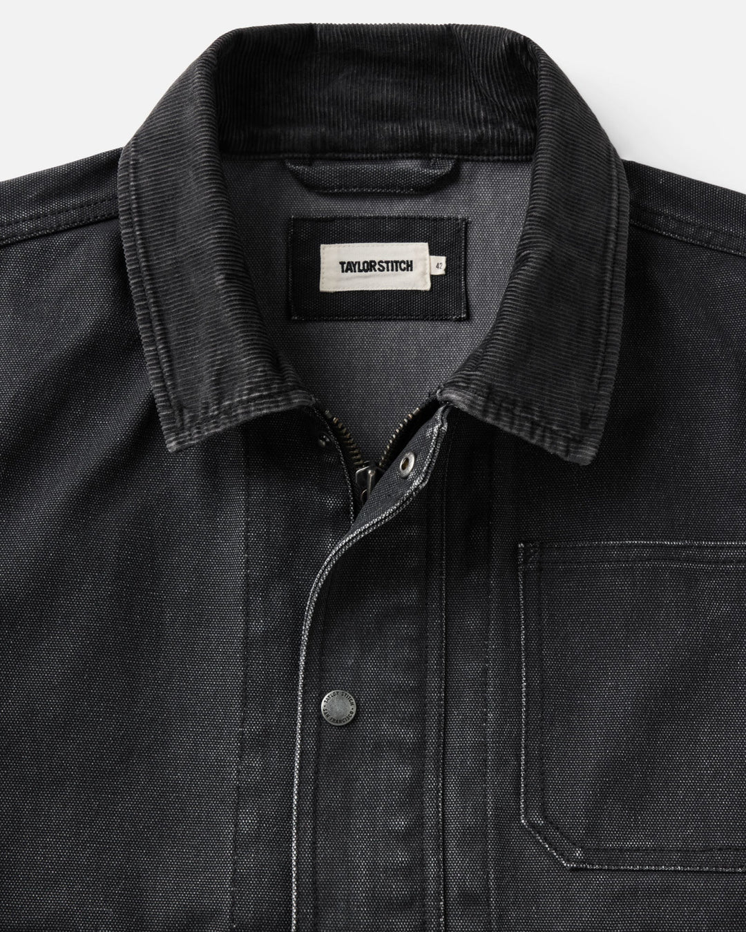 Close-up of a dark charcoal corduroy collar canvas jacket with a pointed collar, a visible neck label reading &