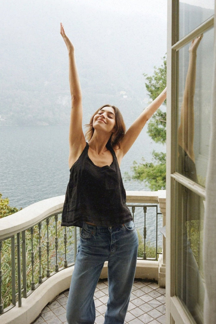Woman with arms raised on a balcony overlooking a scenic view