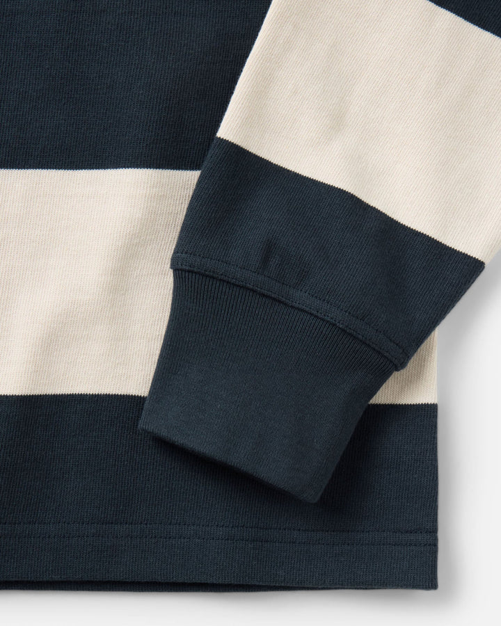 Close-up of a striped Rugby Shirt, showing a navy blue and off-white horizontal stripe pattern with a ribbed cuff and hem.