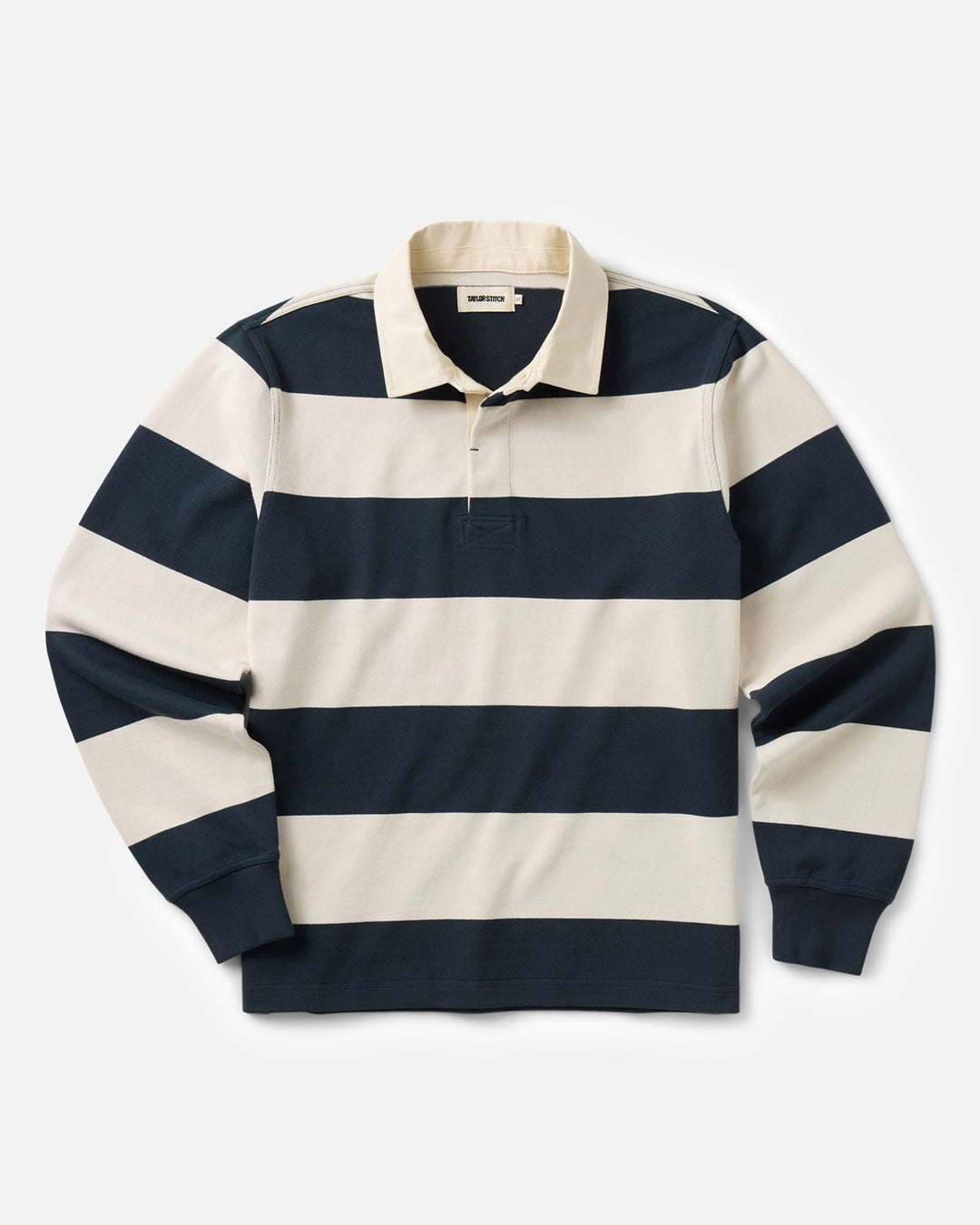 A long-sleeve rugby shirt with horizontal navy blue and cream stripes, featuring a classic collar and a three-button placket, laid flat against a light gray background.