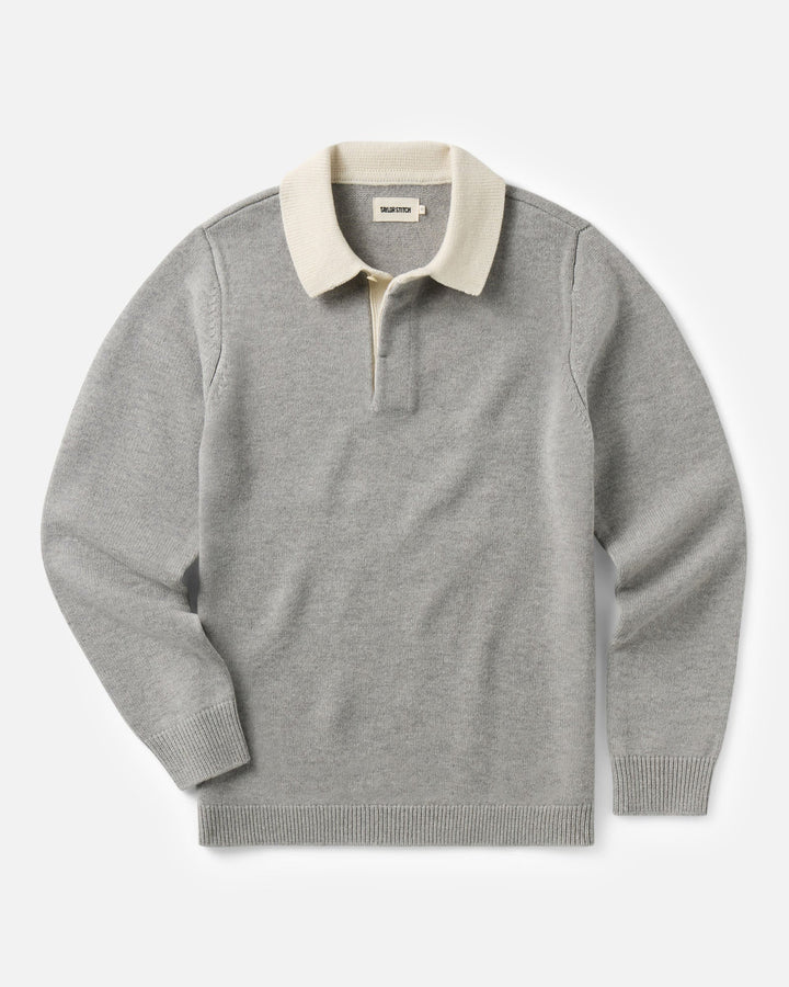 A light gray knit rugby sweater with a contrasting cream-colored collar and a short button placket, displayed flat against a light gray background.