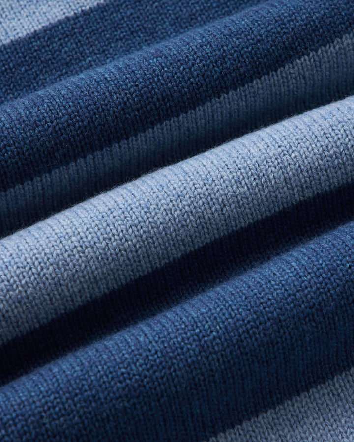 Close-up of a ribbed knit fabric with horizontal stripes in navy blue, medium blue, and light blue.