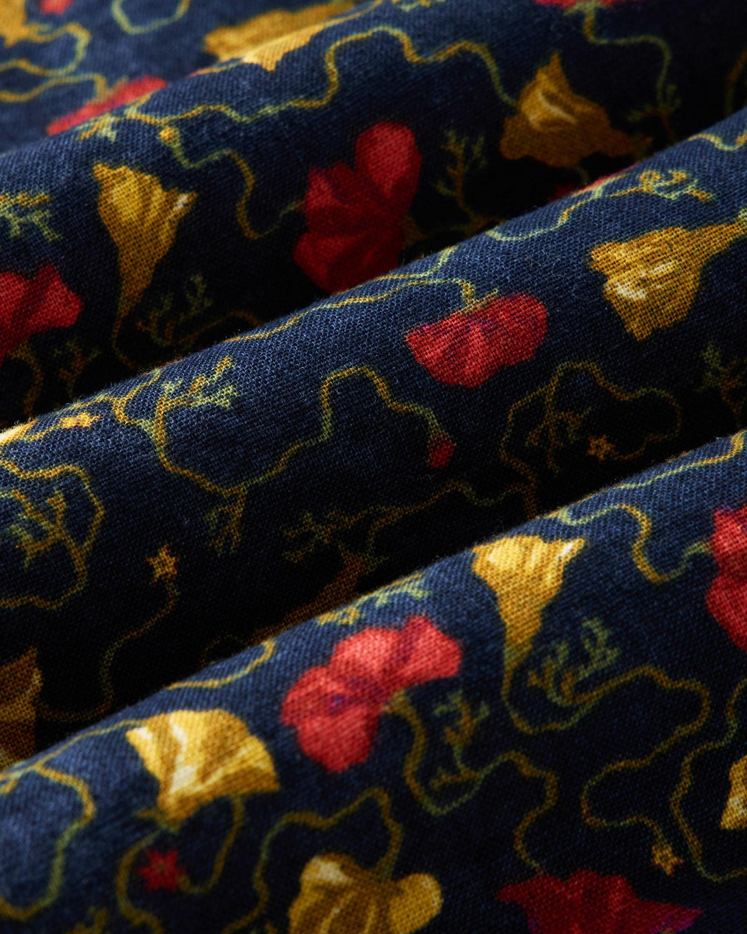 Close-up of patterned fabric with red, yellow, and gold colors on a blue background