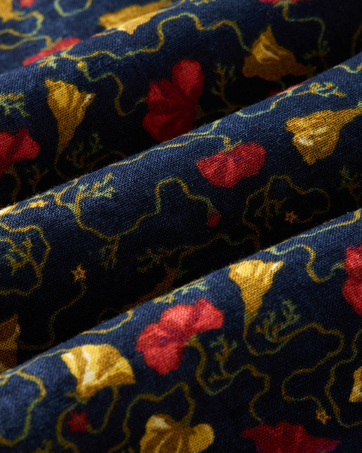 Close-up of patterned fabric with red, yellow, and gold colors on a blue background