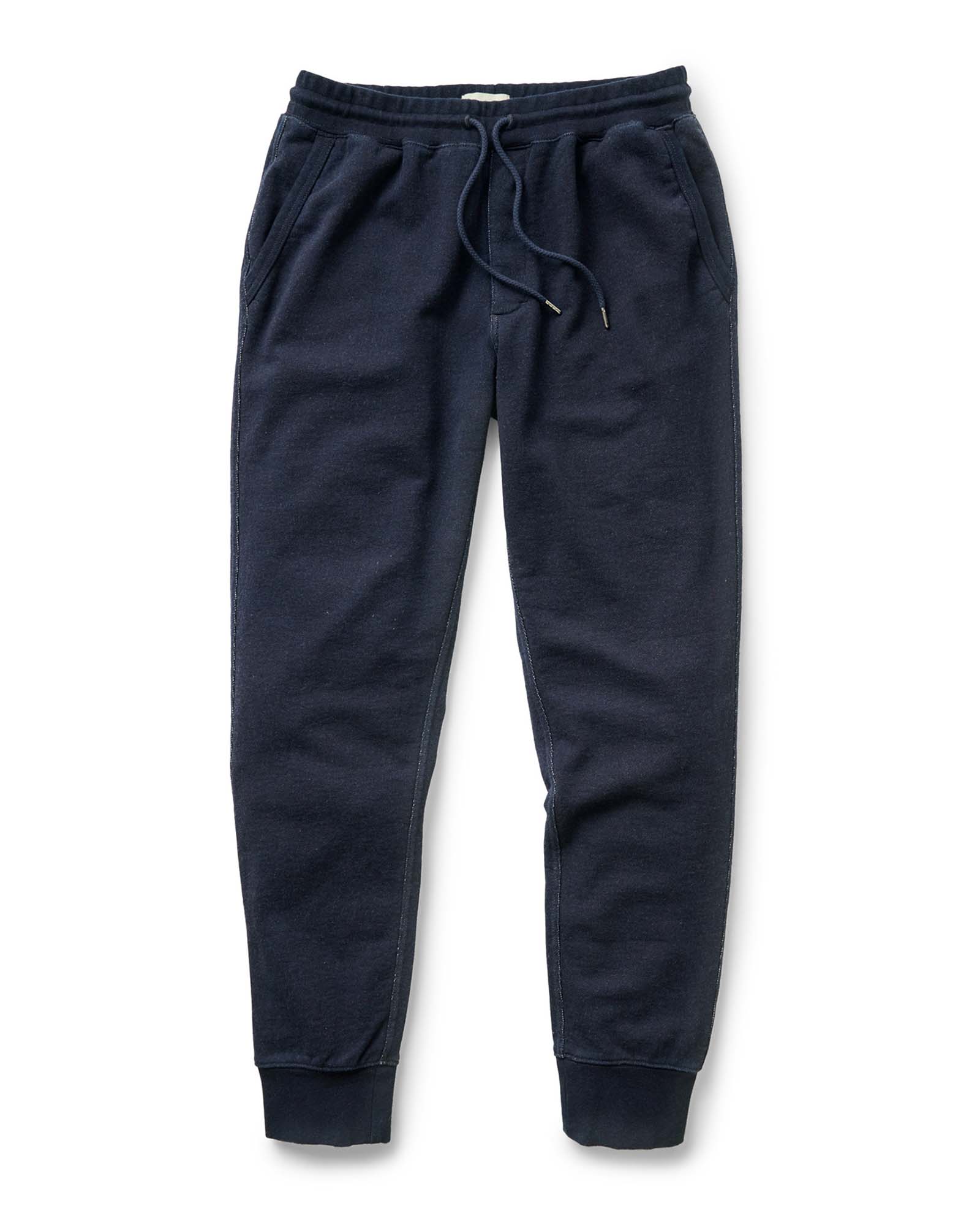 A pair of Taylor Stitch's Sunset Pant in Rinsed Indigo Terry with an elastic waistband, matching drawstring, side pockets, and ribbed ankle cuffs, shown flat on a white background.