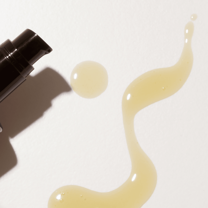 Brown bottle of Apoterra Vetiver Illuminating Oil Cleanser with swatch of cleanser on a white surface