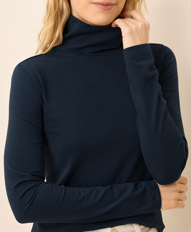 Navy turtleneck sweater worn by a person on a beige background