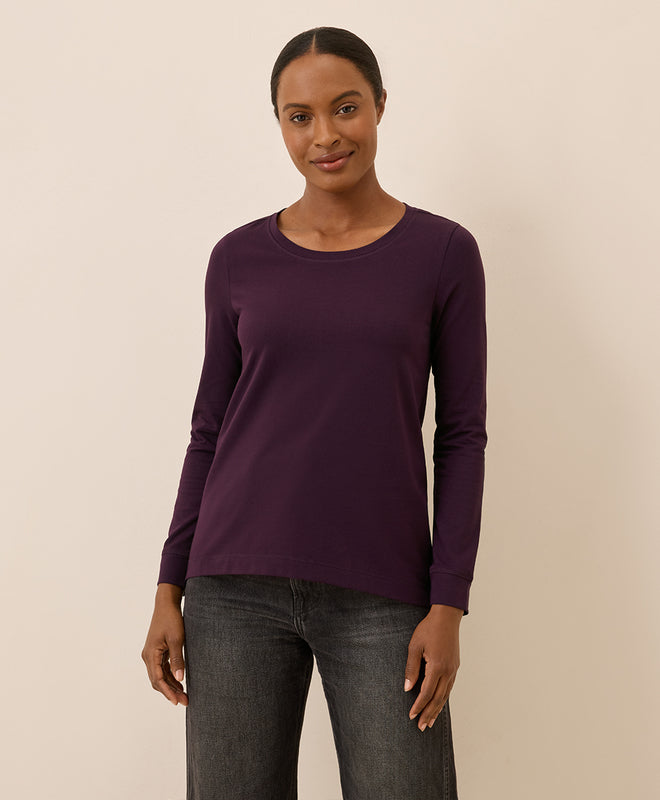 Woman wearing a purple long-sleeve shirt against a beige background
