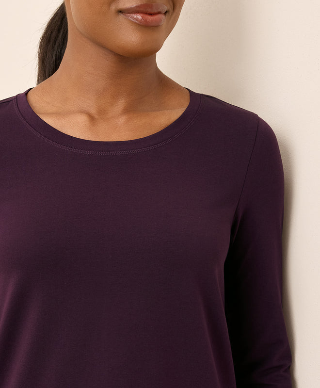 Person wearing a purple long-sleeve shirt against a neutral background