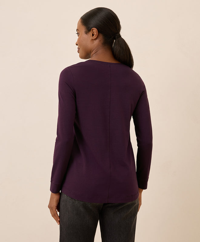 Woman wearing a purple long-sleeve top against a beige background