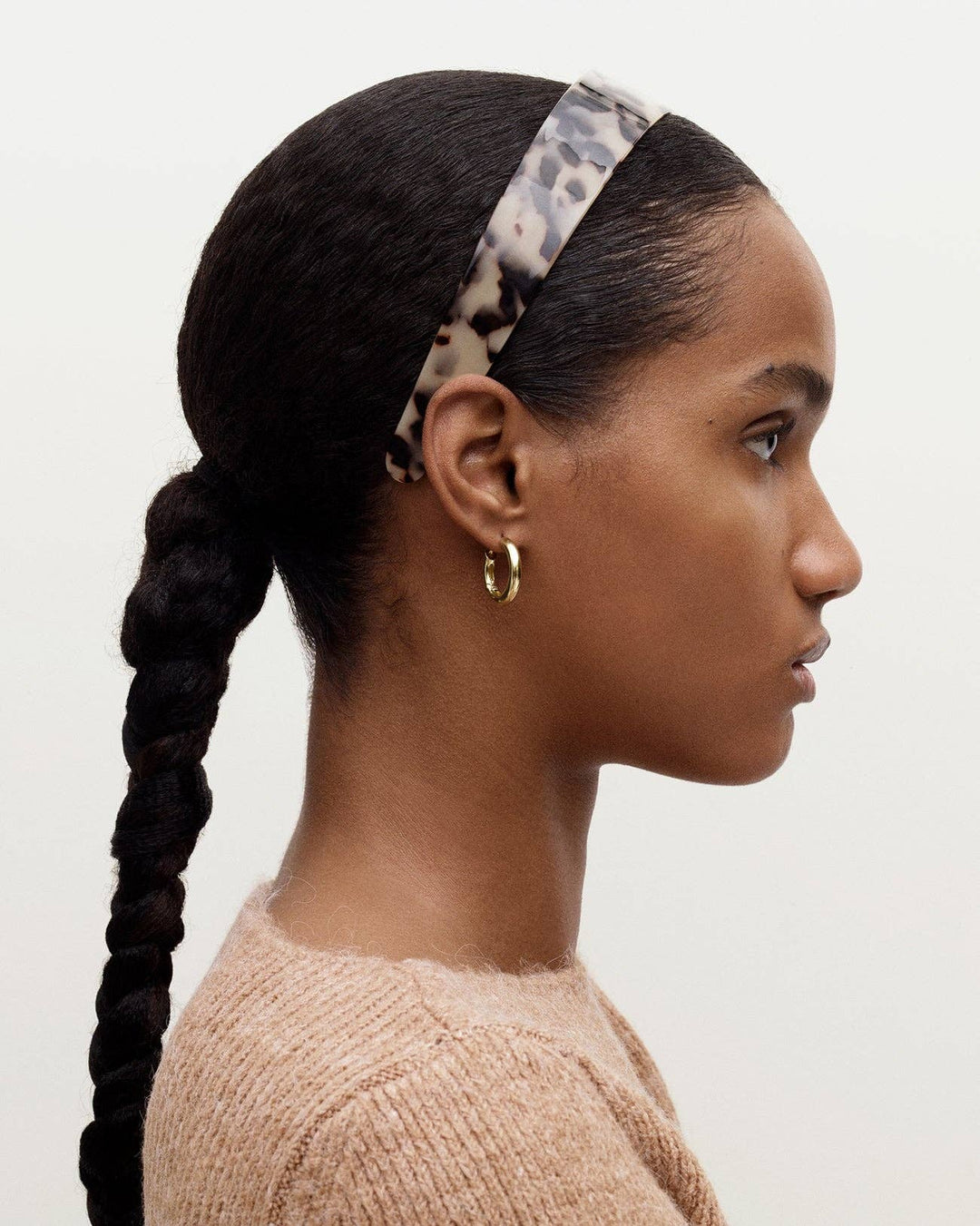 Woman with braided hair wearing a leopard print headband on a white background
