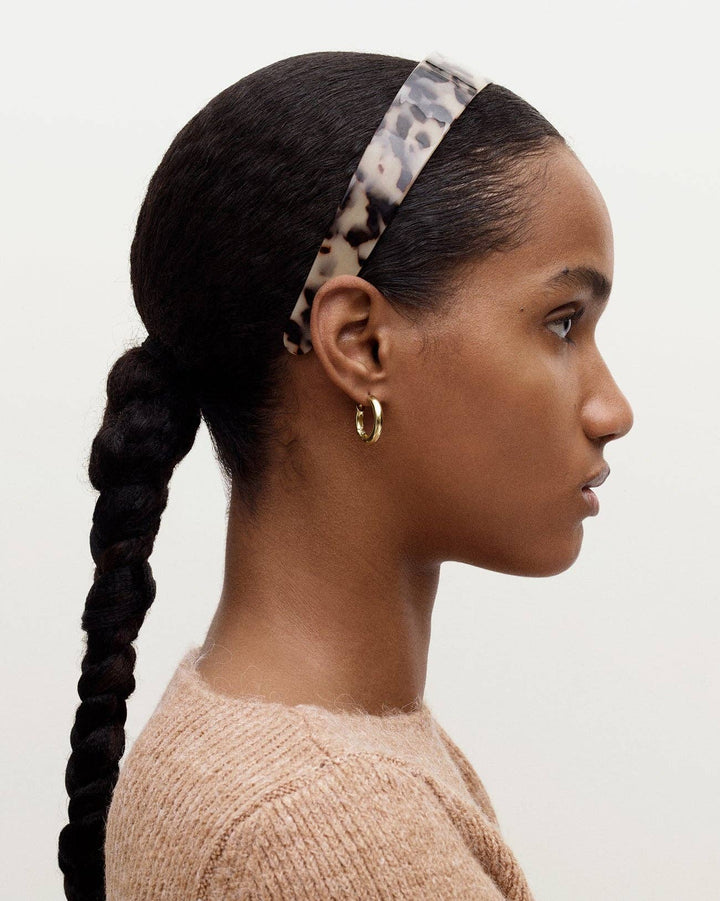 Woman with braided hair wearing a leopard print headband on a white background