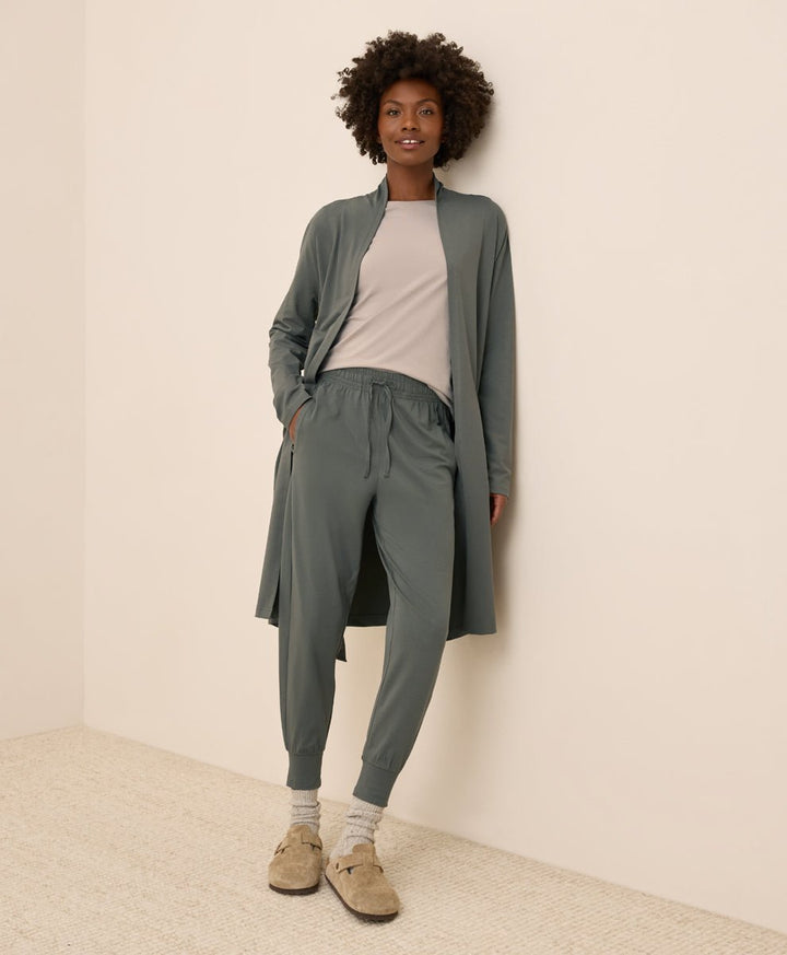 Woman wearing a castor green outfit with a matching duster and pants against a beige background