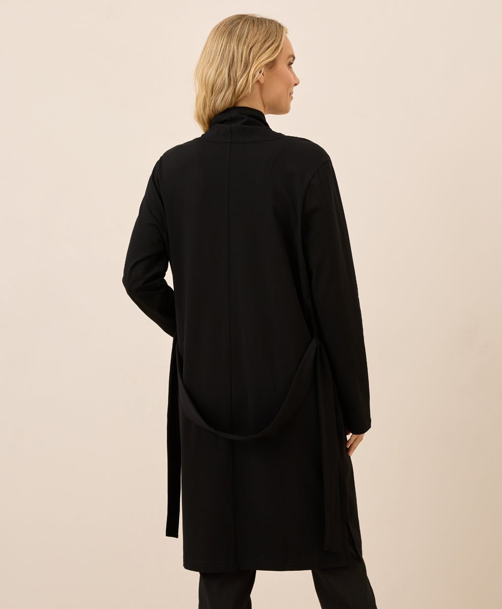 Woman wearing a black coat against a beige background