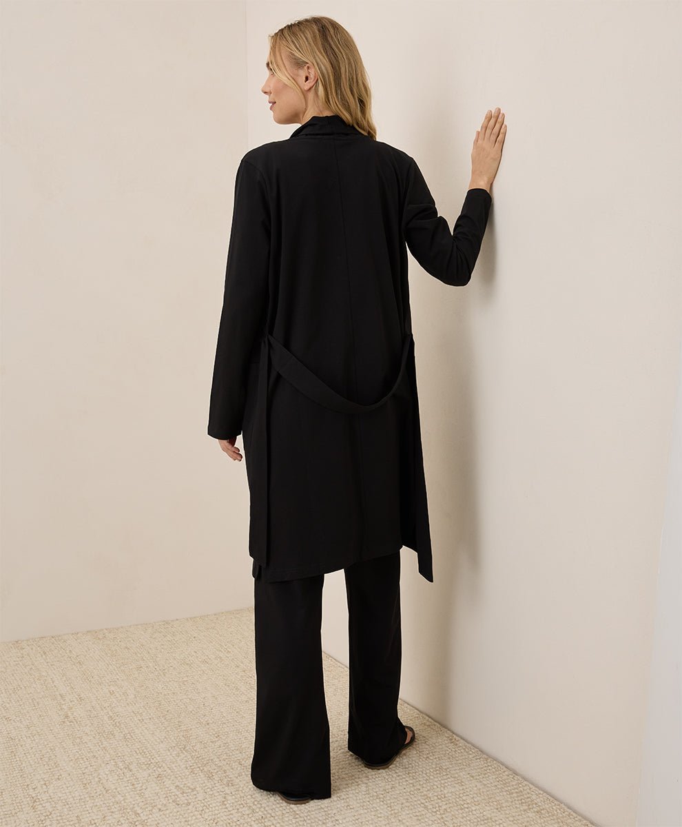 Woman wearing a black outfit against a plain wall