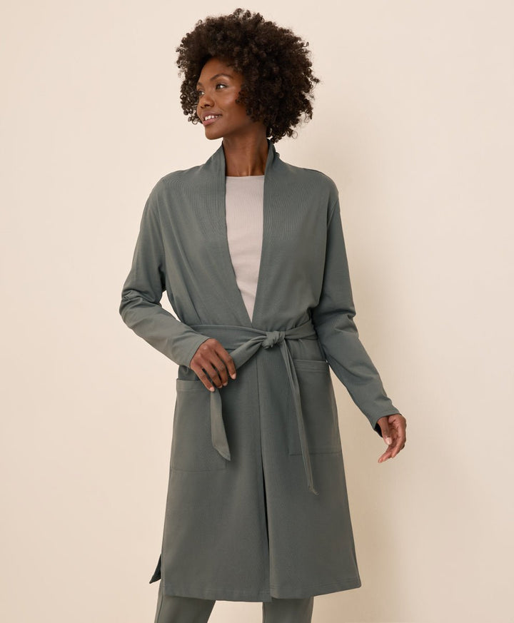 Woman wearing a castor green duster on a beige background
