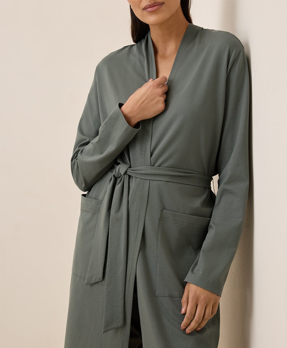 Person wearing a green robe against a beige background