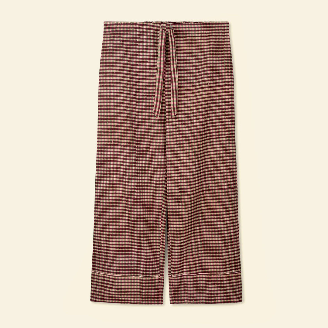 A pair of yonder pajama bottoms featuring a small-scale red and beige gingham pattern, with a matching drawstring waist, displayed flat against a light cream background.