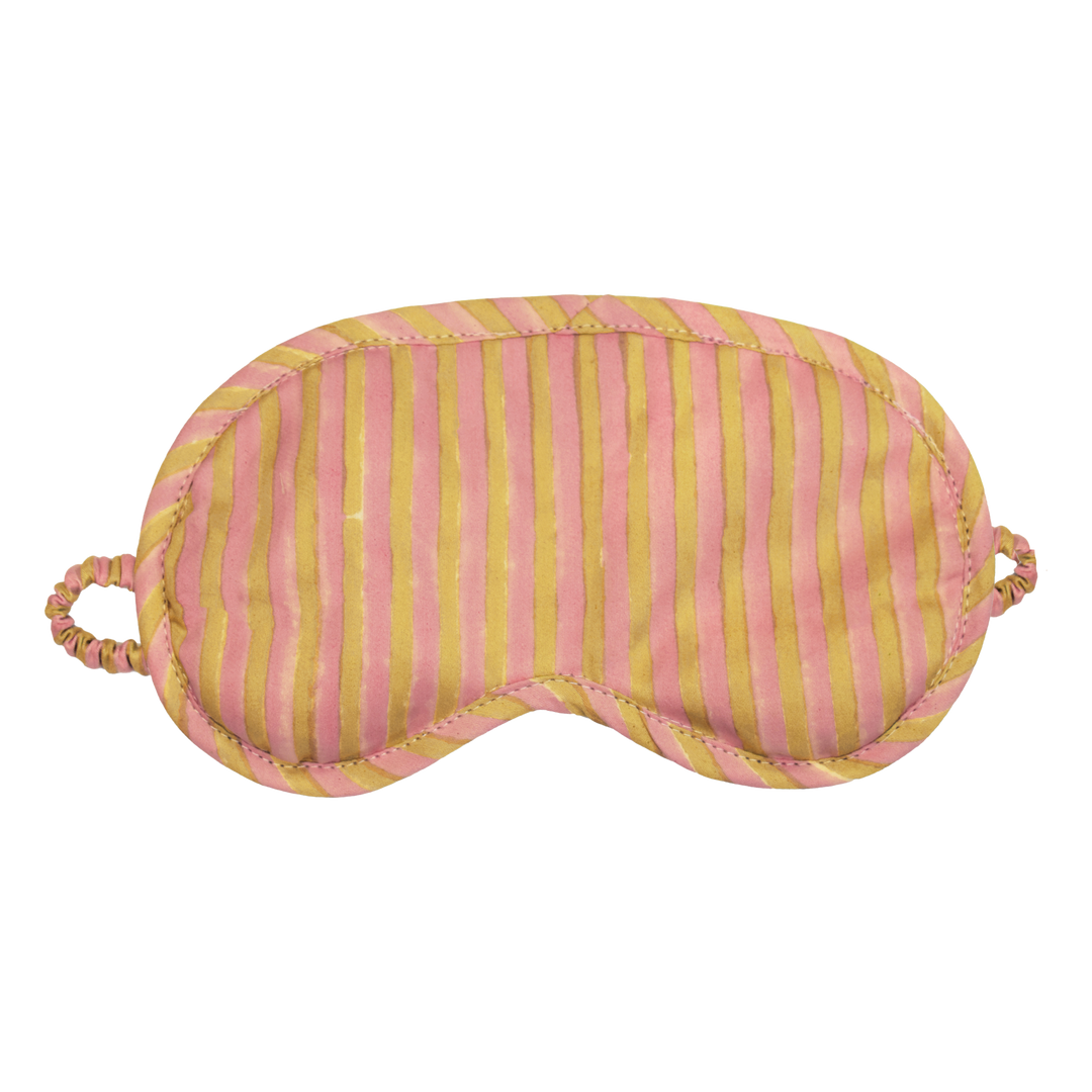 A striped sleep mask with alternating vertical pink and mustard yellow stripes, featuring a padded eye area, stitched edges, and elastic ear loops on a plain white background.