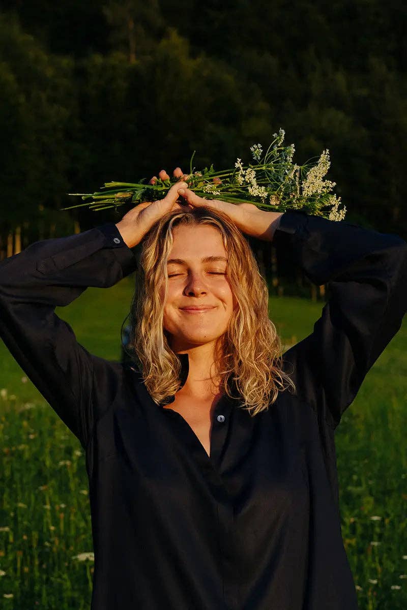 The Essential Shirt Dress - Black - close up view on model, outside in a grassy field with flowers - Echo Market