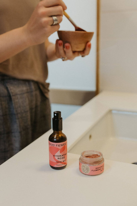 Load image into Gallery viewer, Flowers &amp;amp; Rose Clay Botanical Face Mask - 1 oz - Displayed in use, on a bathroom counter top, next to a hydrating rose facial mist - Echo Market
