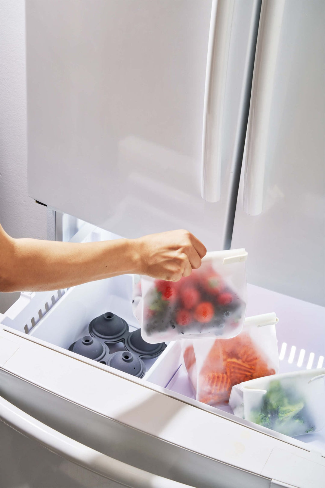 Roll Tight Storage Bag Single - Shown closed and filled with fruits and vegetables as they're loaded into a freezer - Echo Market