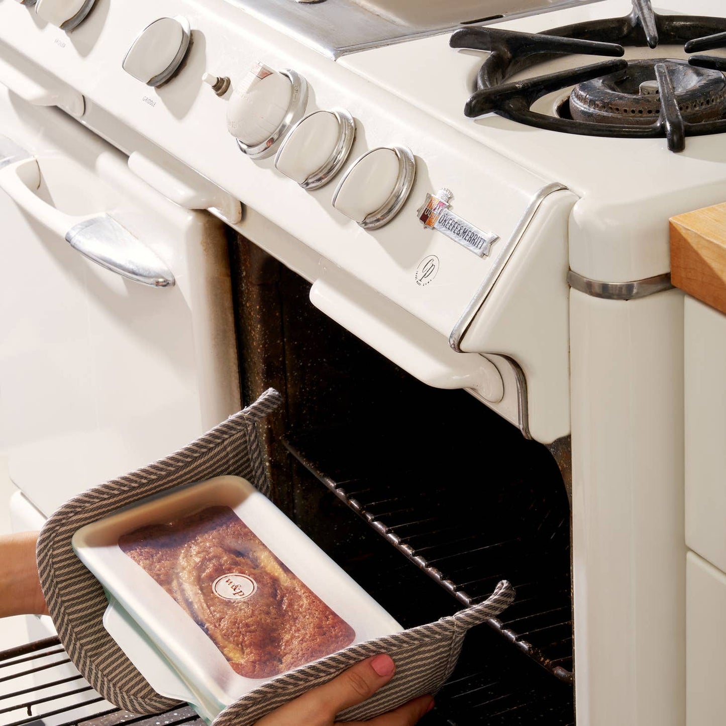 Silicone Stretch Loaf Baking Lids Set - Pictured covering a bread pan containing a fresh loaf as it is taken out of the oven - Echo Market